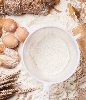 Fırın. Yumurta, ekmek, süzgeç ve un merdanesi.