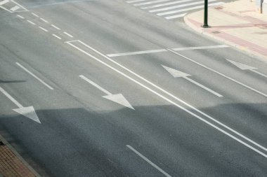 Yol işaretleri beyaz çizgiler ve oklarla boyanmış kaldırımda.