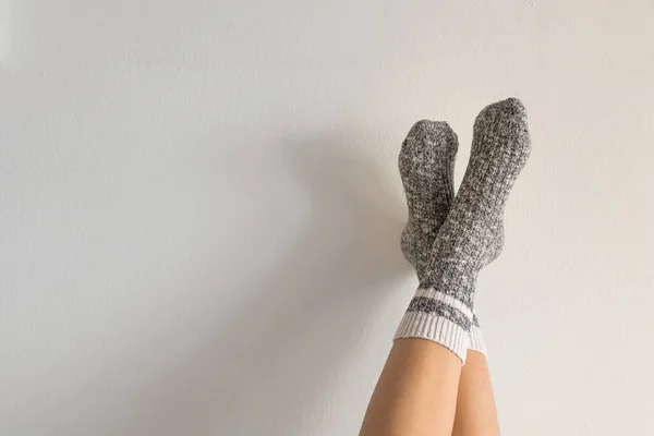 Pijamalı ve çoraplı bir kadının evde kalma kavramına karşı ayaklarını duvara dayadığı yakın plan.