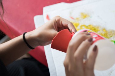 Kartonu yapıştırıp el işi yapan bir kızın yakın çekimi.