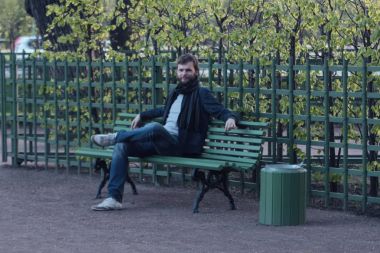 Yaz bahçesinde bankta oturan genç adam. St. Petersburg, Rusya. Ünlü yerler.