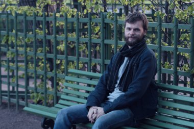 Yaz bahçesinde bankta oturan genç adam. St. Petersburg, Rusya. Ünlü yerler.