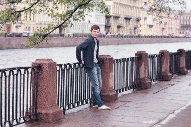 Fontanka Nehri dolgu üzerinde yürüyen genç adam. St. Petersburg tarihi merkezi.