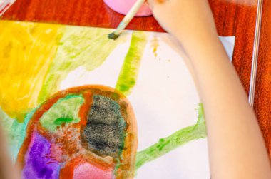 Çocuk anaokulu kızı kağıda parlak boyalar çizerek suluboya çiziyor, yakın plan. çocuklar için evde eğitim