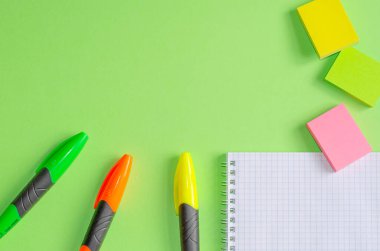 Okul konseptine geri dönelim. Okul ve ofis malzemeleri ofis masasında, yeşil arka plan. Kopyalama alanı olan düz.