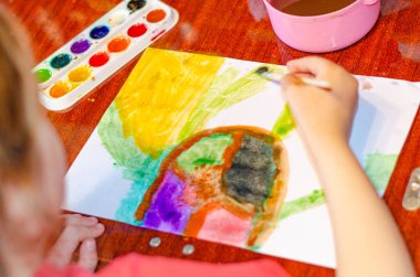 Çocuk anaokulu kızı kağıda parlak boyalar çizerek suluboya çiziyor, yakın plan. çocuklar için evde eğitim