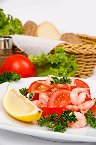 Salade aux crevettes et tomates sur une assiette blanche avec une portion — Photo