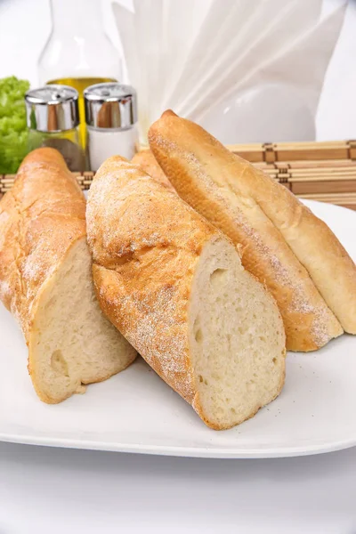 Hembakat bröd baguette på en vit platta dekorerad med sallad — Stockfoto