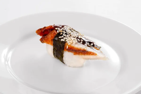 Sushi à l'anguille fumée sur une assiette blanche sur fond blanc . — Photo