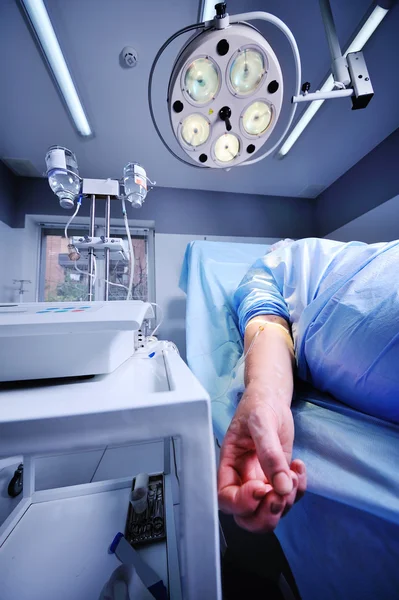 Pacjent z kroplówki w żyły na tle operacyjnych chirurgicznych — Zdjęcie stockowe