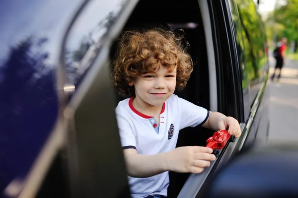 Baby boy looks out the car window — Stock Photo, Image