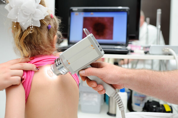 the doctor examines the patients mole