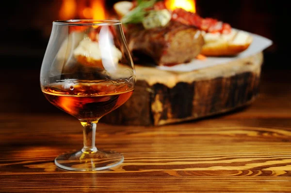 Glass of cognac on the background  a meat dish — Stock Photo, Image