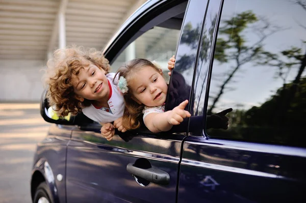 Children look out from a car window — Stock Photo, Image