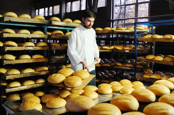 Пекар на фоні полиць з хлібом — стокове фото