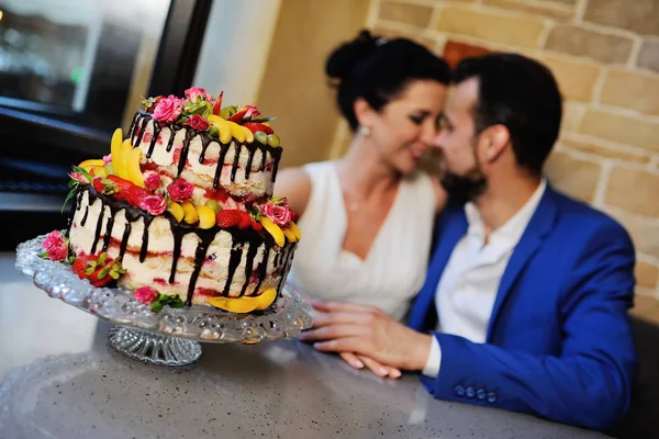 Noiva e noivo beijando no fundo de um bolo de casamento — Fotografia de Stock