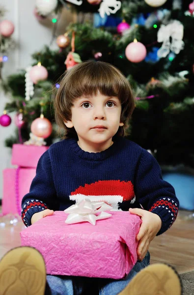 Un niño con un regalo sobre un fondo del árbol de Navidad — Foto de Stock