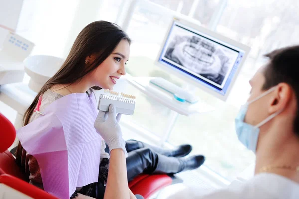 Cute young girl in dentists chair.the selection of the color of teeth — Stock Photo, Image