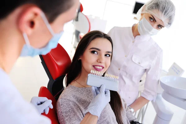 Linda chica joven en dentistas chair. La selección del color de los dientes — Foto de Stock