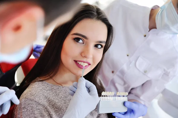 Мила молода дівчина в стоматологічному кріслі.підбірка кольору зубів — стокове фото