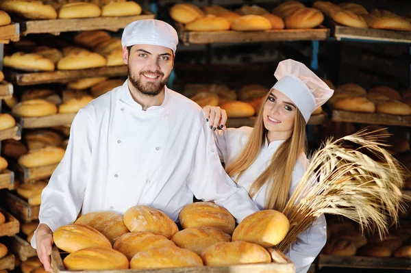 Дівчина з хлопцем у білому комбінезоні на фоні пекарні — стокове фото