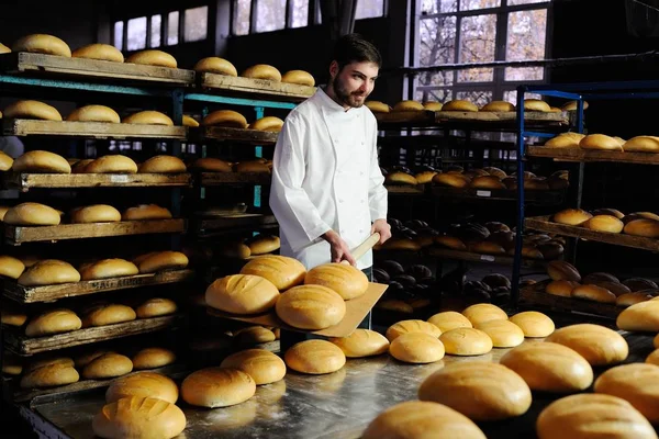 Пекар витягує з печі свіжий хліб — стокове фото