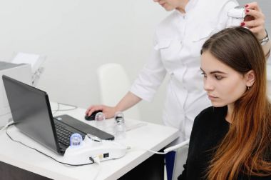 özel bir cihaz kullanarak bir hasta kadın saç dermatolog inceliyor