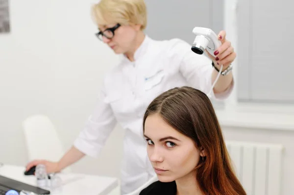 Dermatólogo examina el cabello de una mujer paciente usando un dispositivo especial —  Fotos de Stock