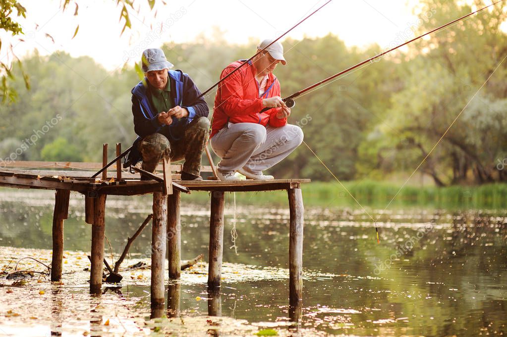 Two fishermen catch fish standing on the bridge
