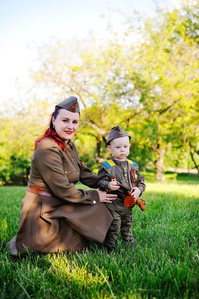 Child and woman dressed in military uniform against nature background