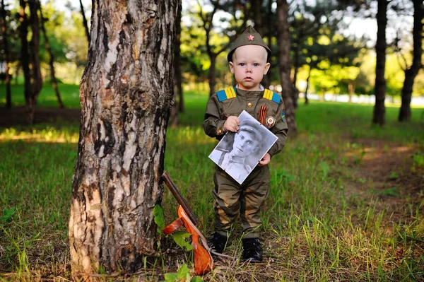 Child in military uniform with a photo of a veteran of the Second World War — Stock Photo, Image