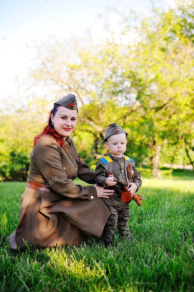 Child and woman dressed in military uniform against nature background