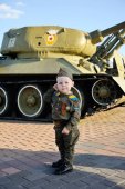 Kind in Militäruniform auf dem Panzerhintergrund