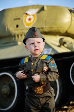 Tank arka plan üzerinde askeri üniformalı çocuk