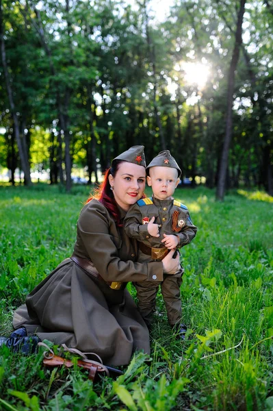 Enfant et femme vêtus d'un uniforme militaire sur fond de nature — Photo