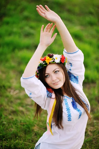 Ukrainian girl in a shirt and a floral wreath on her head pullin — Stock Photo, Image