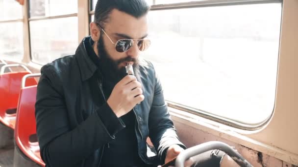 Chico fuma cigarrillo electrónico en un tranvía — Vídeos de Stock