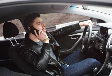 Genç adam bir araba sürüş sırasında telefonda konuşurken