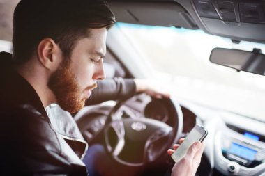 Genç adam bir araba sürüş sırasında telefonda konuşurken