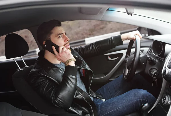 Jovem falando ao telefone enquanto dirige um carro — Fotografia de Stock