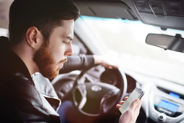 Genç adam bir araba sürüş sırasında telefonda konuşurken
