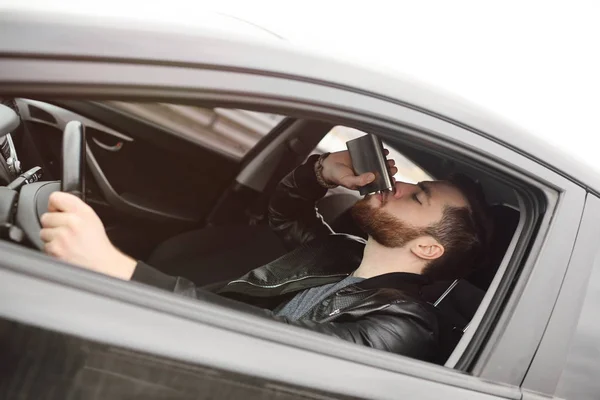 Joven conduciendo un coche con un matraz de hierro —  Fotos de Stock