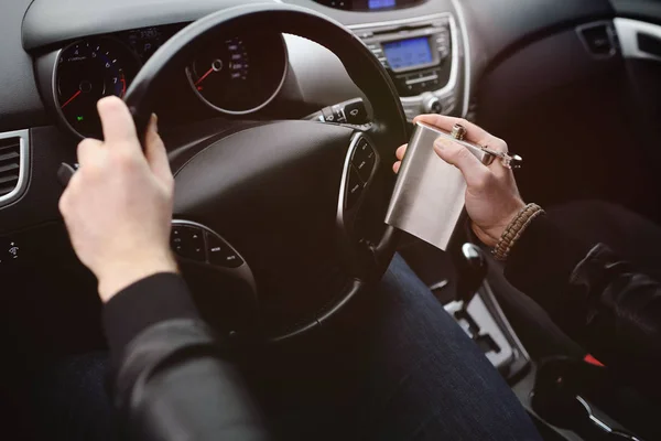 Joven conduciendo un coche con un matraz de hierro —  Fotos de Stock