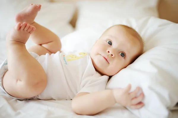 Retrato de bebê com olhos azuis. Uma criança descansando em uma cama — Fotografia de Stock