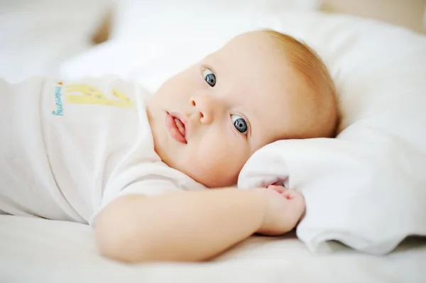 Portrét miminko s modrýma očima. Dítě na lůžku — Stock fotografie