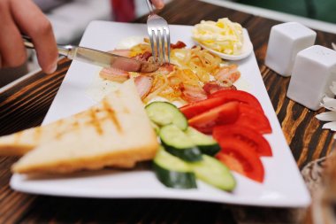 Kahvaltı - ekmek ve tereyağı sahanda yumurta ve domuz pastırması domates ile bir arka plan üzerinde ve salatalık ahşap arka plan üzerinde