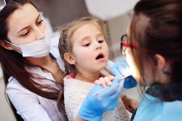 Bebé ayudando a un dentista a examinar a un paciente — Foto de Stock