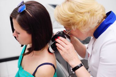 Dermatolog mol veya akne olan bir dermatoscope hastanın inceliyor