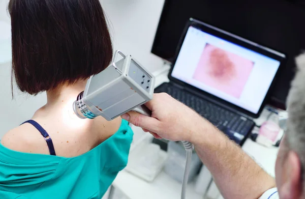 O médico examina neoplasias ou toupeiras na pele dos pacientes — Fotografia de Stock