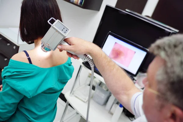 Le médecin examine les tumeurs ou les grains de beauté sur la peau des patients — Photo